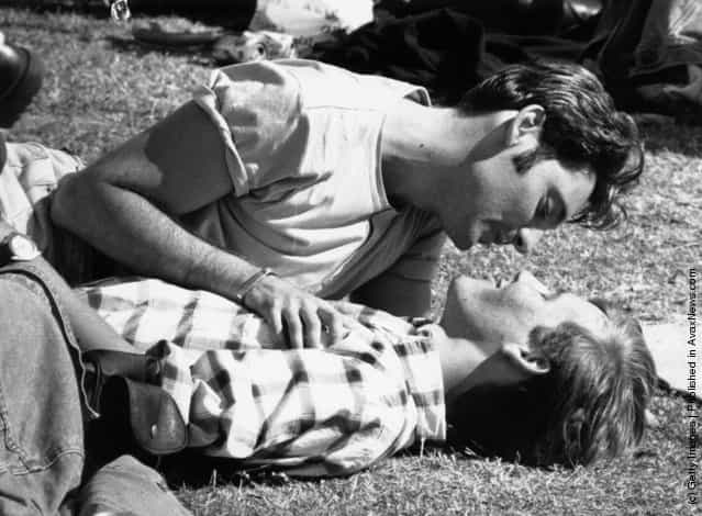 Two young men sharing a tender moment on the grass during a Gay Pride festival in London, 1996