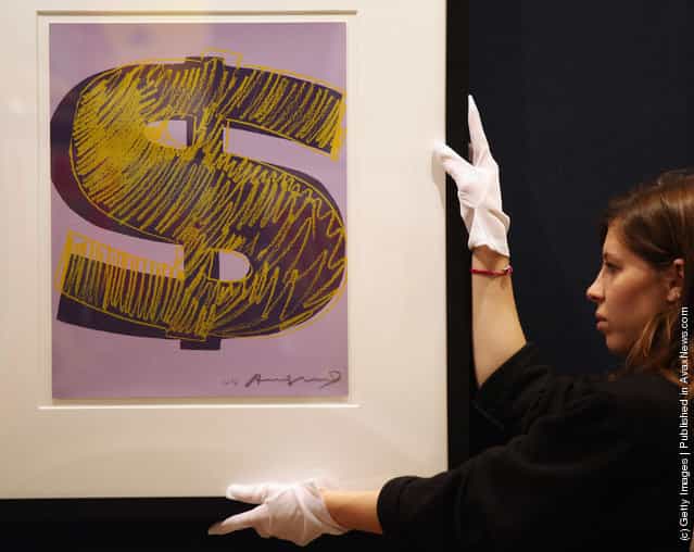 A gallery assistant adjusts a print of an Andy Warhol artwork estimated to fetch 20,000 GBP in Bonhams auction house
