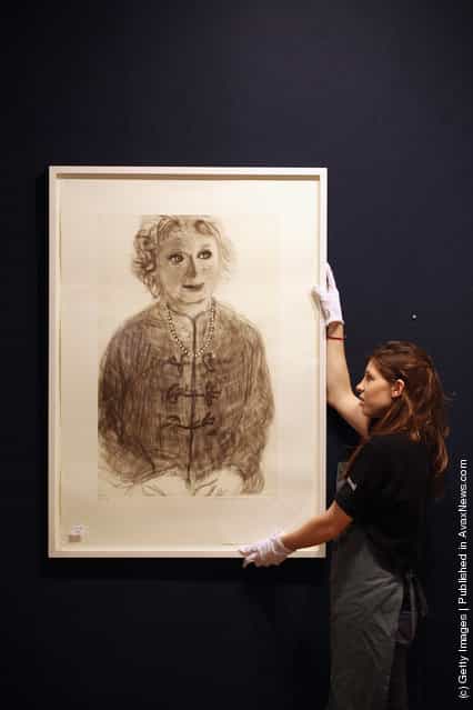 A gallery assistant adjusts a print of a David Hockney artwork entitled Soft Celia estimated to fetch 5,000 GBP in Bonhams auction house