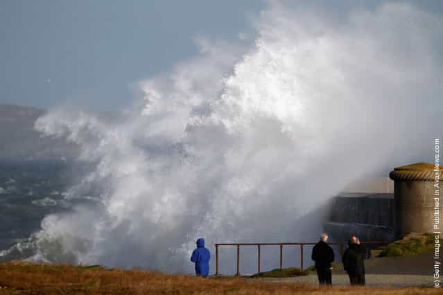 People watch waves crash over the Holyhead breakwater as the search continues for the crew of cargo vessel The Swanland which sank off north Wales on November 27, 2011 in Holyhead, Wales