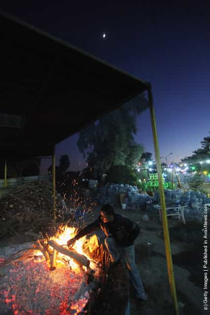 A worker prepares the traditional Iraqi fish dish Masgouf over a fire at an outdoor restaurant along the Tigris River