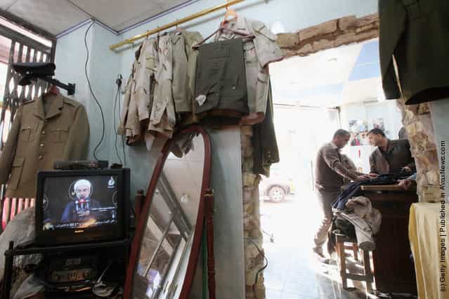 People gather in a shop that sells uniforms to members of Iraqs military and police forces as a religious video plays