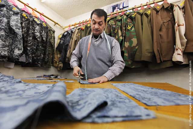 A tailor cuts cloth while making a police unform in a shop that sells uniforms to members of Iraqs military and police forces