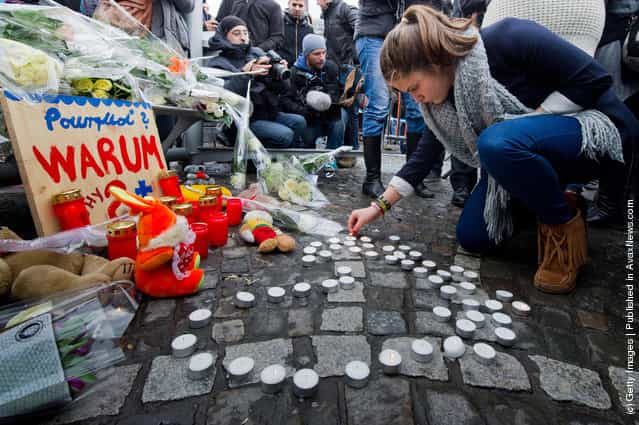 A woman lights candles as people react to yesterday's gun and grenade attack in central Liege