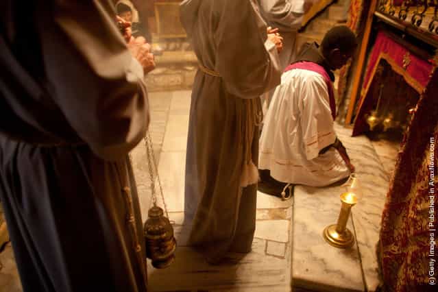 Monks pray on the spot in the Grotto in the Church of the Nativity