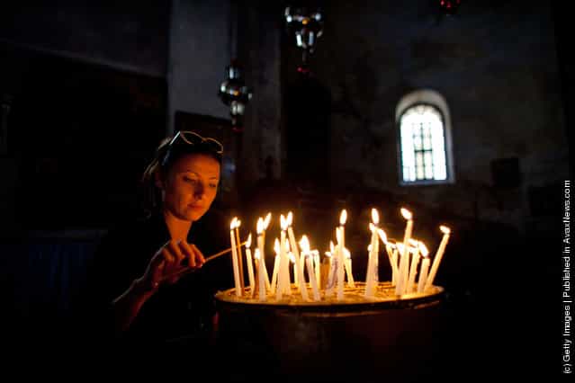 A woman lights candles as she prays in the Church