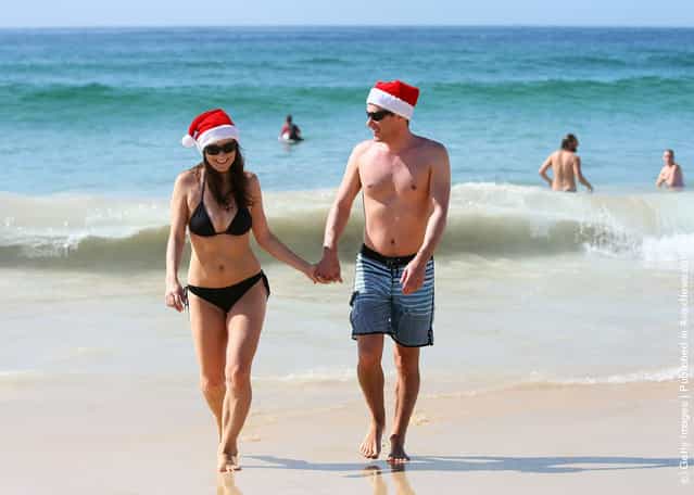 Vivian Vasso and Ben Cheathan stroll hand in hand from the water at Bondi Beach on December 25, 2011 in Sydney, Australia