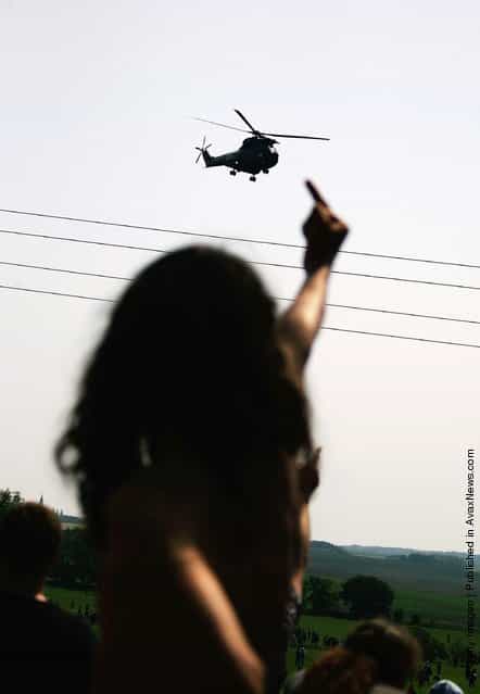 An activist of the anti-G8 forum Block G8 shows his middle finger to a police helicopter passing overhead