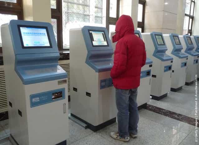 A passenger picks up tickets from a ticket machine after booking on the Internet at Beijing Railway Station