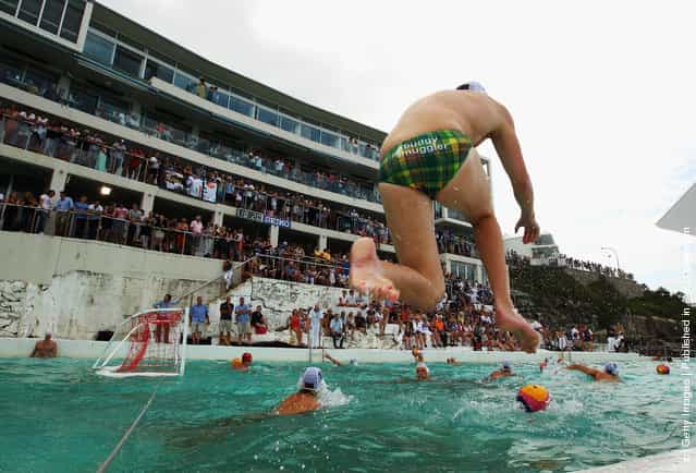 An Australian team member jumps into the water during warm-up before the Water Polo by the Sea match between Australia and the United States of America at at Bondi Icebergs on Bondi Beach