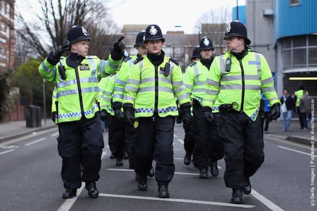 QPolice officers make there way past the Loftus Road stadium as searches are made of football fans prior to the FA Cup Fourth Round between Queens Park Rangers and Chelsea
