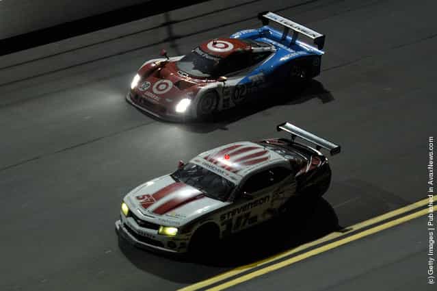The #57GT Camero GTR driven by Robin Liddell, John Edwards, and Ronnie Bremer race with the #02 DP Target/TELMEX driven by Scott Dixon, Dario Franchitti, Juan Pablo Montoya and Jamie McMurray during the Rolex 24 at Daytona International Speedway