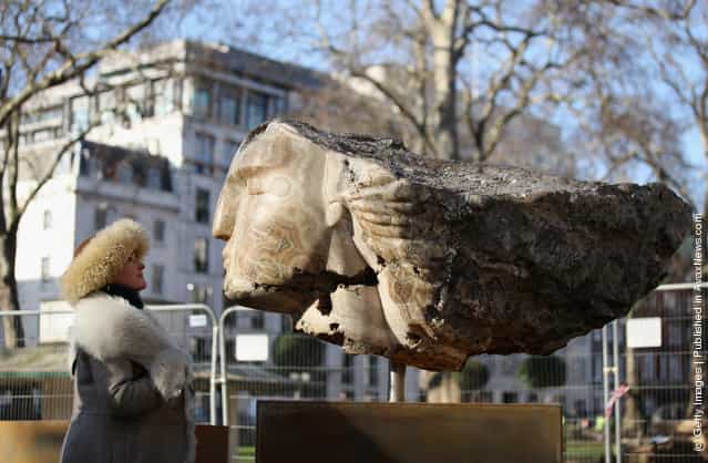 British sculptor Emily Young poses for a photograph with a large stone head she created in Berkeley Square