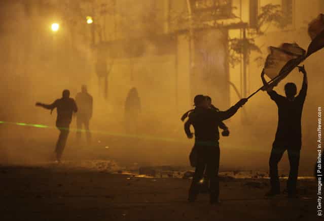 Protesters run through clouds tear gas fired by security forces in Cairo, Egypt