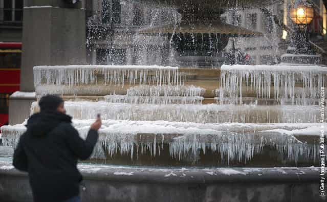 Visitors take phone pictures of the frozen fountains in Trafalgar Square