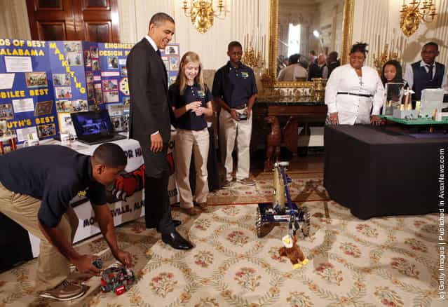 U.S. President Barack Obama (2L) watches a robot with Robert Knight III (L), Morgan Ard (3L) and Titus Walker (C), eighth-grade students at Monroeville Jr. High School in Monroeville, Alabama, who won high honors at the South BEST robotics competition, while touring student science fair projects on exhibit in the State Dining Room at the White House