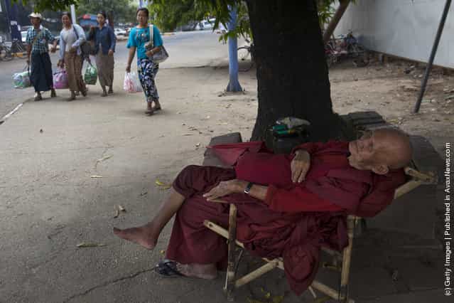 A Burmese monk sleeps under the shade of a tree during a hot afternoon