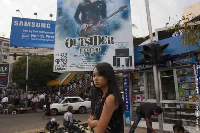 A woman walks past a movie poster in the central shopping area of the city in Yangon, Myanmar