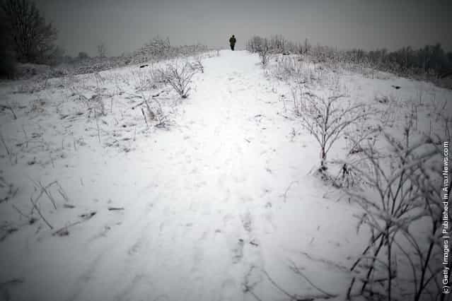 A man walks up a snow covered hill on Wimbledon common on February