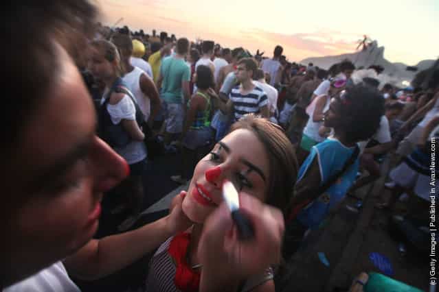 A man paints a womans face during Carnival celebrations along Ipanema beach in Rio de Janiero, Brazil