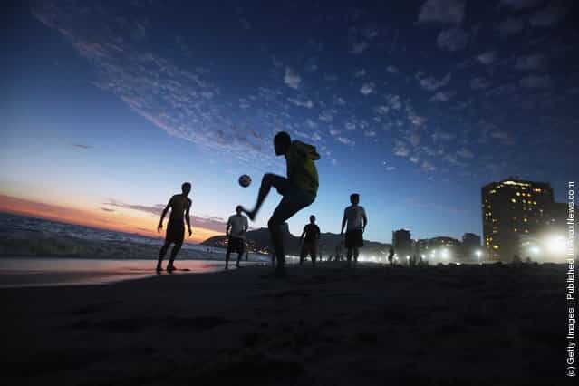 Brazilian revelers play soccer at sunset during Carnival celebrations along Ipanema beach