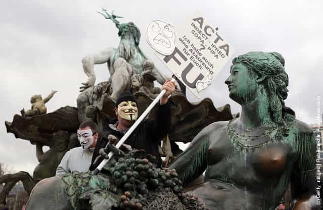 Activists protest from inside the Neptune fountain at Alexanderplatz during a demonstration against the Anti-Counterfeiting Trade Agreement (ACTA)