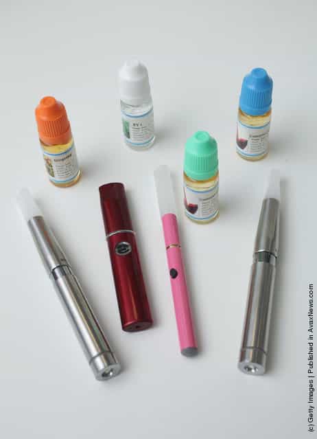 Electronic cigarettes lie in front of bottles containing the flavoured liquids they use at a shop