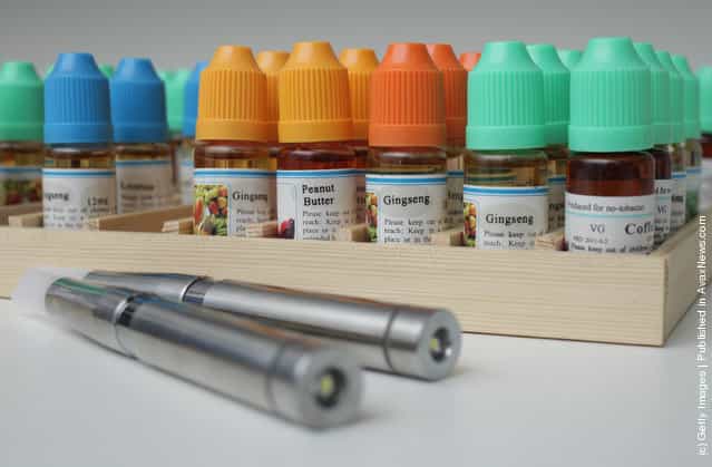 Two electronic cigarettes lie in front of bottles containing the flavoured liquids they use at a shop