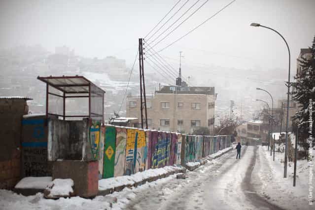 A man walks down a hill as snow falls on March 2, 2012 in Hebron, West Bank