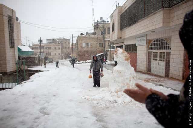 People walk on a snow covered street on March 2, 2012 in Hebron, West Bank