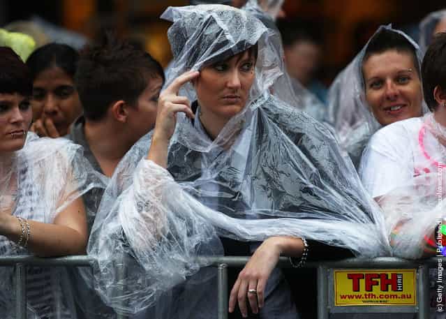 Crowd members attempt to keep dry with umbrellas and ponchos prior to the 2012 Sydney Gay & Lesbian Mardi Gras Parade