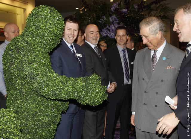 Prince Charles, Prince of Wales is introduced to people dressed as living topiary statues during his visit to the Ideal Home Show