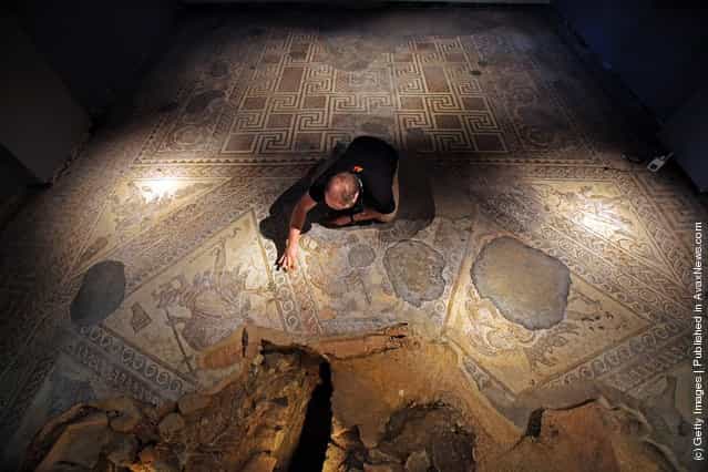 David Rawcliffe, house and monument steward at the National Trusts Chedworth Roman Villa cleans a Roman mosiac in the new environmentally-controlled conservation shelter near Cirencester, England