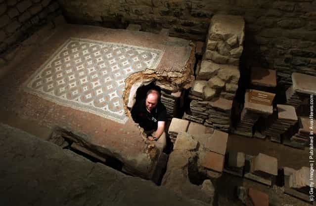 David Rawcliffe, house and monument steward at the National Trusts Chedworth Roman Villa cleans a Roman mosiac in the new environmentally-controlled conservation shelter near Cirencester, England