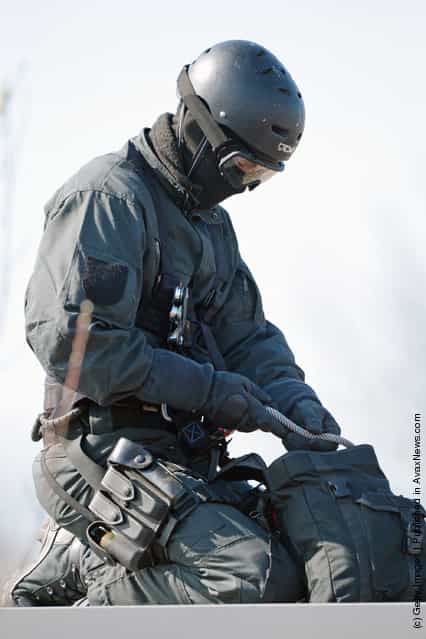 A Member of Germanys elite police unit, the Spezialeinsatzkommando, or SEK, packs up his equipment after demonstrating an abseil deployment from a helicopter during a media event