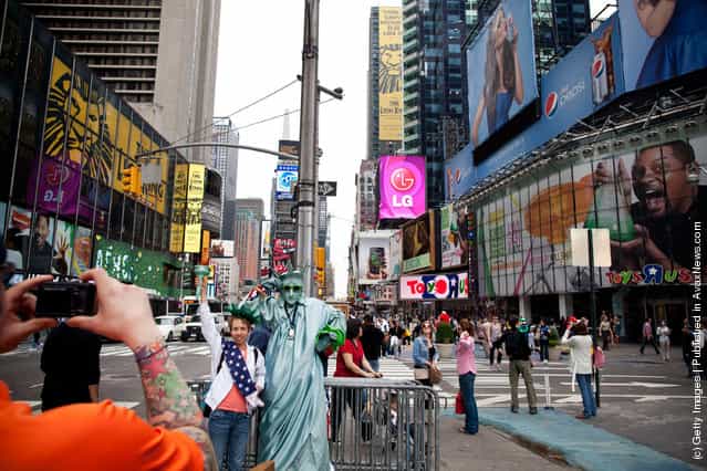 A tourist has her photo taken with a man dressed up as the Statue of Liberty in Times Square