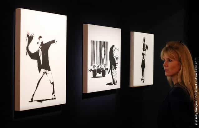 Employee Leonora Oldfield looks at Banksys (L-R) Love is in the Air, Leopard and Barcode and Bomb Hugger at Bonhams