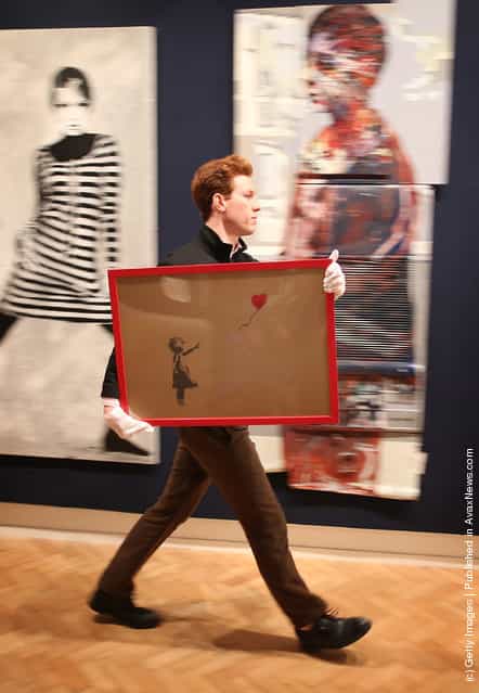 Employee George Foren holds Banksys Girl and Balloon, which was painted on an Ikea frame, at Bonhams auctioneers