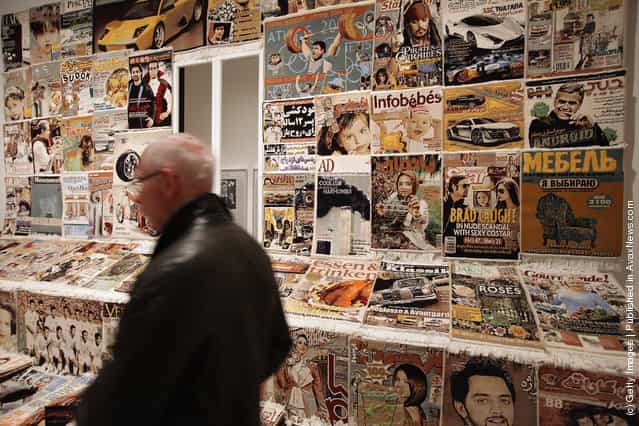 A visitor walks through an installation of carpets in the likeness of magazine covers by Iranian artist Fahrad Moshiri at the exhibition ARTandPRESS at Martin Gropius Bau