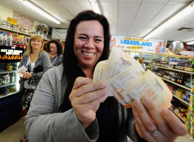 Victoria Vazquez displays $280 worth of Mega Millions lottery tickets for her office pool that she purchased at Liquorland