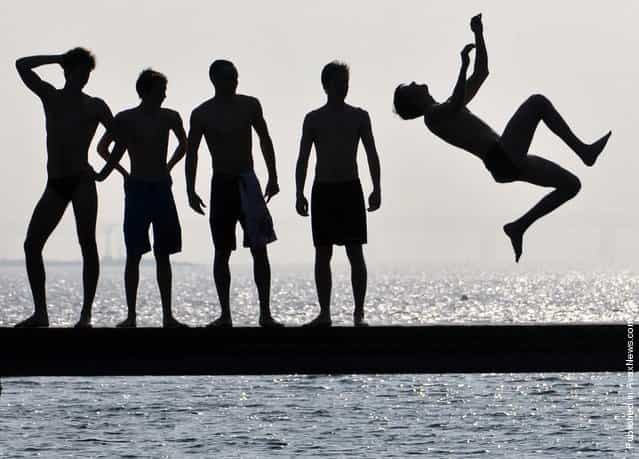 Boys jump in the water on the first sunny day of spring in Malmo, Sweden