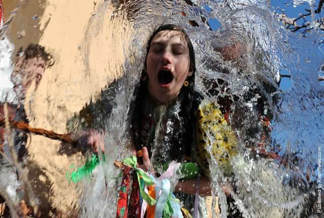 Young Slovaks dressed in traditional costumes throw a bucket of water at a girl as part of Easter celebrations in the village of Trencianska Tepla, Slovakia, April 9, 2012. Slovakia's men splash women with water to symbolize youth, strength and beauty for the upcoming spring season