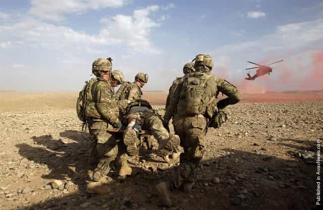 U.S. Army soldiers carry an injured comrade to a helicopter during a firefight with Taliban in the Maiwand district of Kandahar province, southern Afghanistan, April 9, 2012