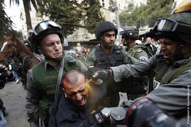 Israeli border police officers use pepper spray as they detain an injured Palestinian protester during clashes on Land Day after Friday prayers outside Damascus Gate in Jerusalem's Old City, March 30. Israeli security forces fired rubber bullets, tear gas and stun grenades to break up groups of Palestinian stone-throwers as annual Land Day rallies turned violent