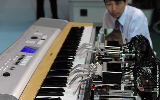 A man watches a piano-playing robot in action during the Taipei International Robot Show on October 19, 2010. Some 300 exhibitors from 66 companies took part in the four-day exhibition