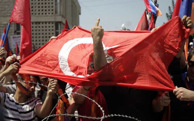 A Lebanese Armenian man gestures obscenely through a torn Turksih flag during a protest outside the Turkish embassy in Rabieh, northeast of Beirut, to commemorate the 97th anniversary of the Ottoman Turkish genocide against the Armenian people on April 24, 2012