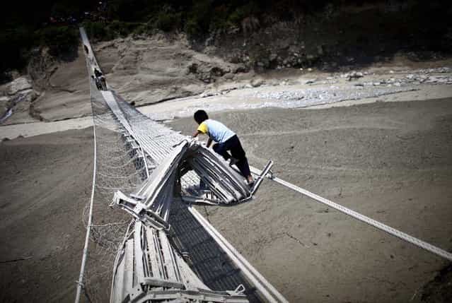 Villagers try to cross the Seti river through a damaged suspension bridge about 125 miles west of Katmandu, Nepal
