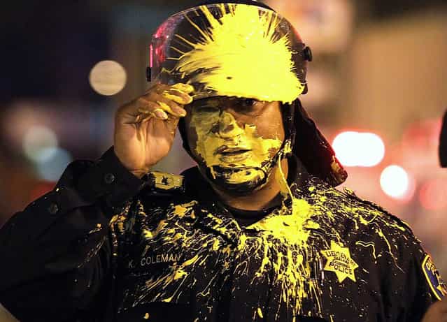 An Oakland police officer pauses after being hit in the face with paint as officers advanced on Occupy protesters blocking an intersection during a May Day demonstration in Oakland, California on May 2, 2012