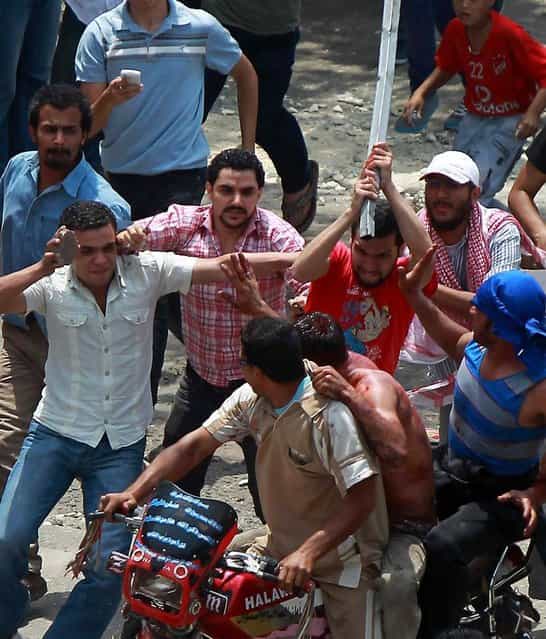 Egyptian protesters beat a man as he tries to escape on the back of a motorcycle after he was accused of attacking demonstrators in the Abbassiya district of Cairo on May 2
