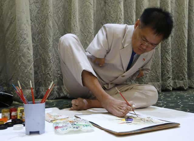 Ng Ah Kwai, 50, of Penang, Malaysia, who was born with deformed arms, paints with his foot during the Mouth and Foot Painting Convention in Singapore May 1, 2012